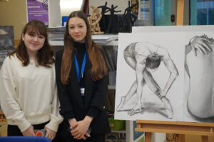 Two IB DP students looking to the camera showing their amazingly detailed pencil and graphite drawing of a ballerina at the recent IB DP options evening